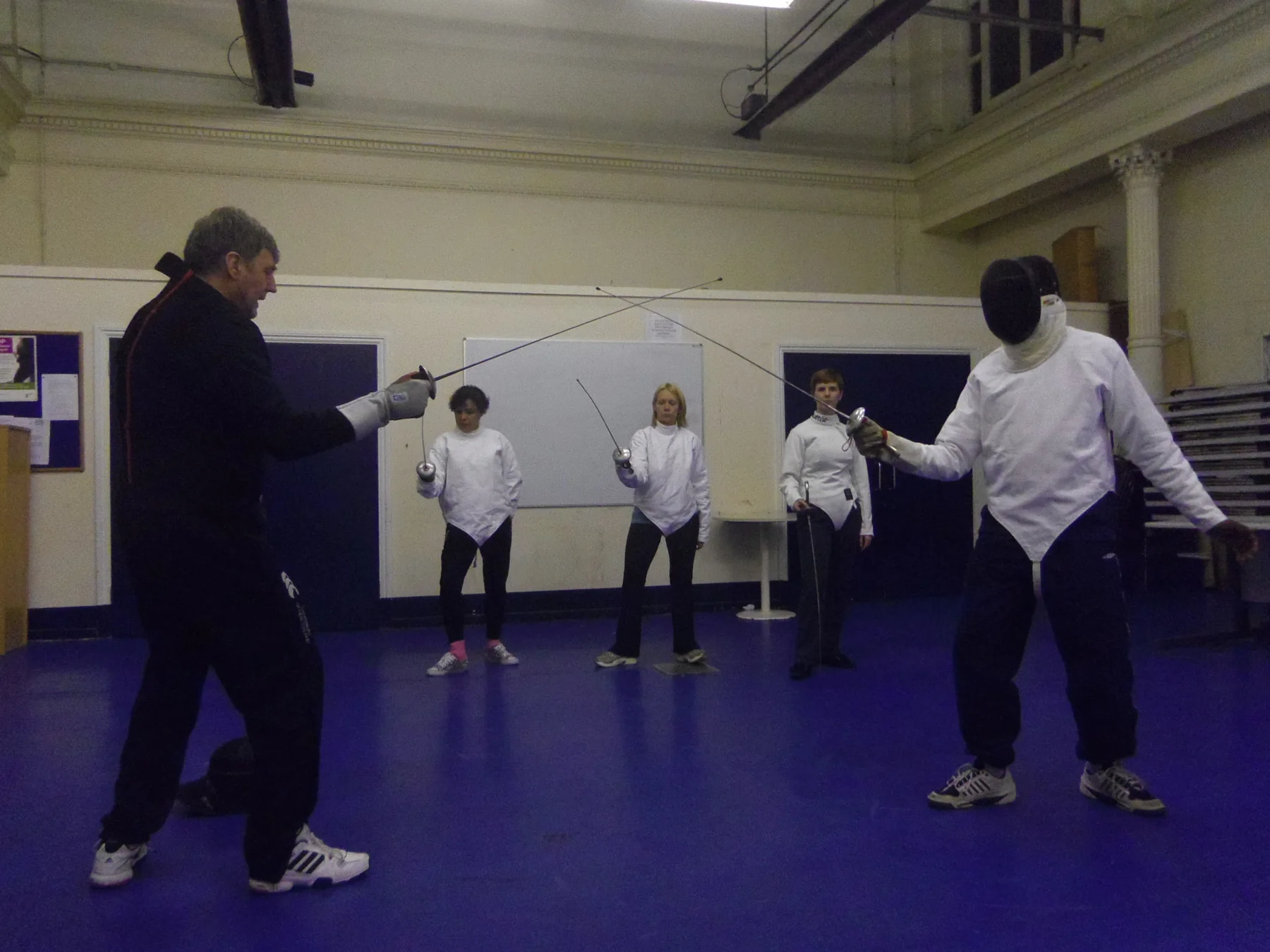 A coach demonstrating fencing technique to the group