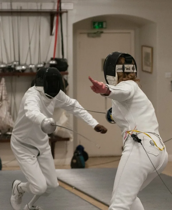 Two masked fencers exchanging attacks