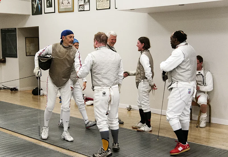 A group of fencers talking beside the piste