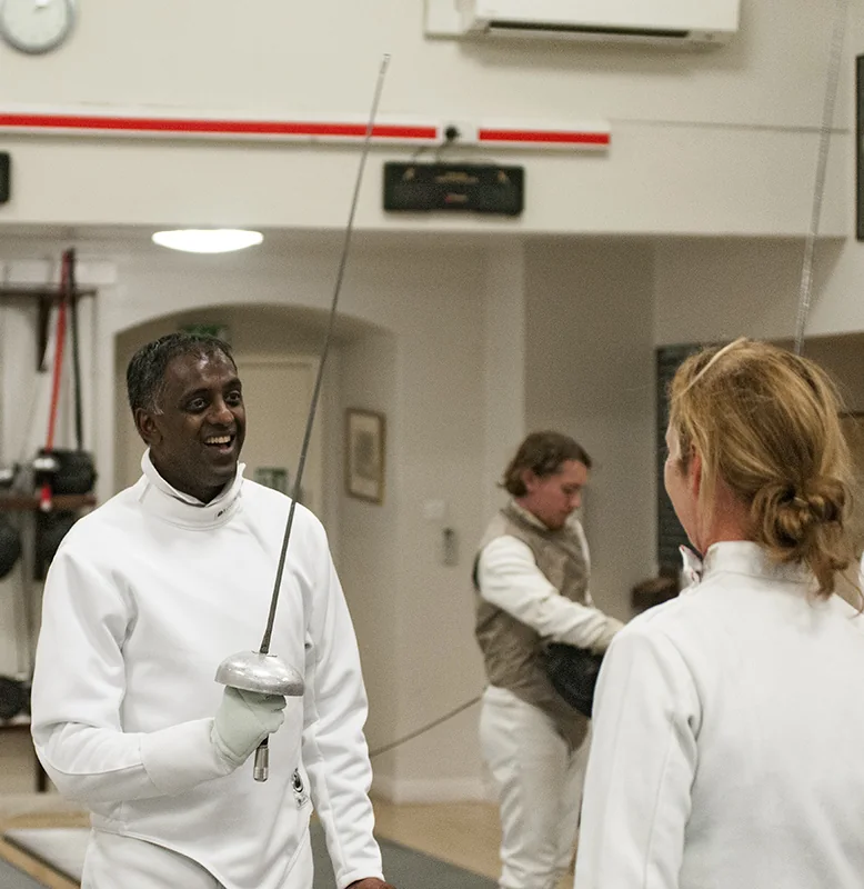 Two club members smiling during fencing practice