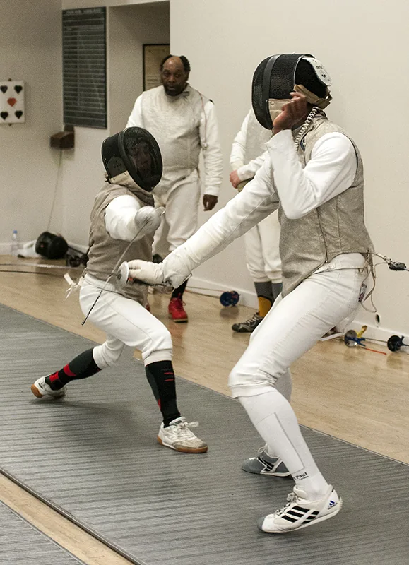 Two fencers exchanging hits on the piste
