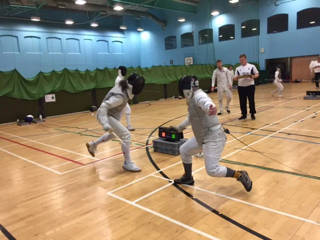 Two fencers lunging towards each other during a bout