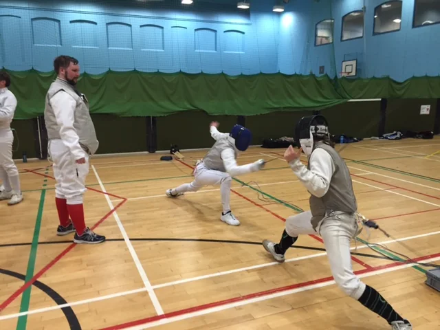 A foil fencer lunging during a competition bout